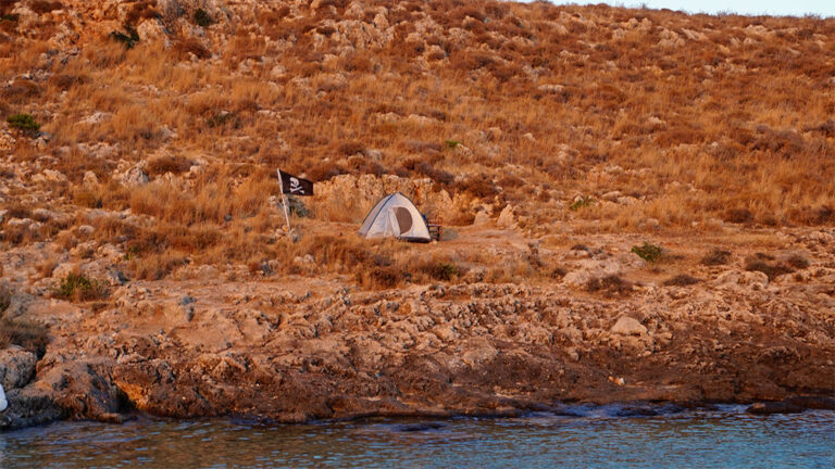 Tent with a pirate flag at a beach at Cape Tainaron in Greece