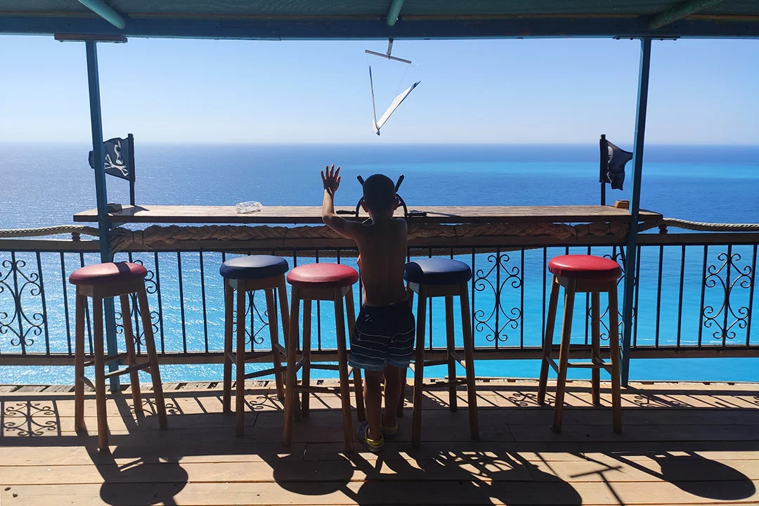 Little boy playing like a pirate on a wooden platform over the sea in Lefkas island