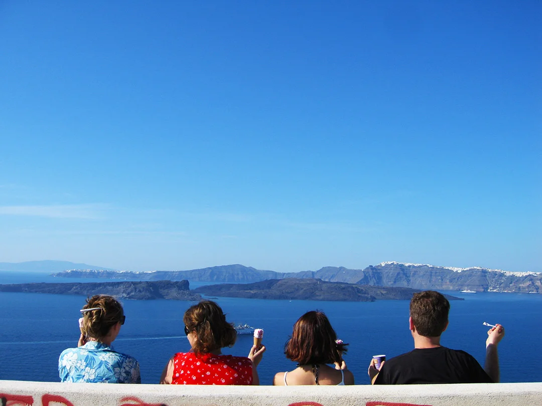 Four people enjoying ice-cream with a view of Santorini island in Greece
