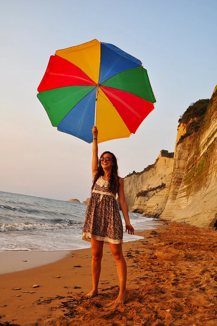 Woman with a big colorful umbrella at Loggas beach in Corfu Island Greece